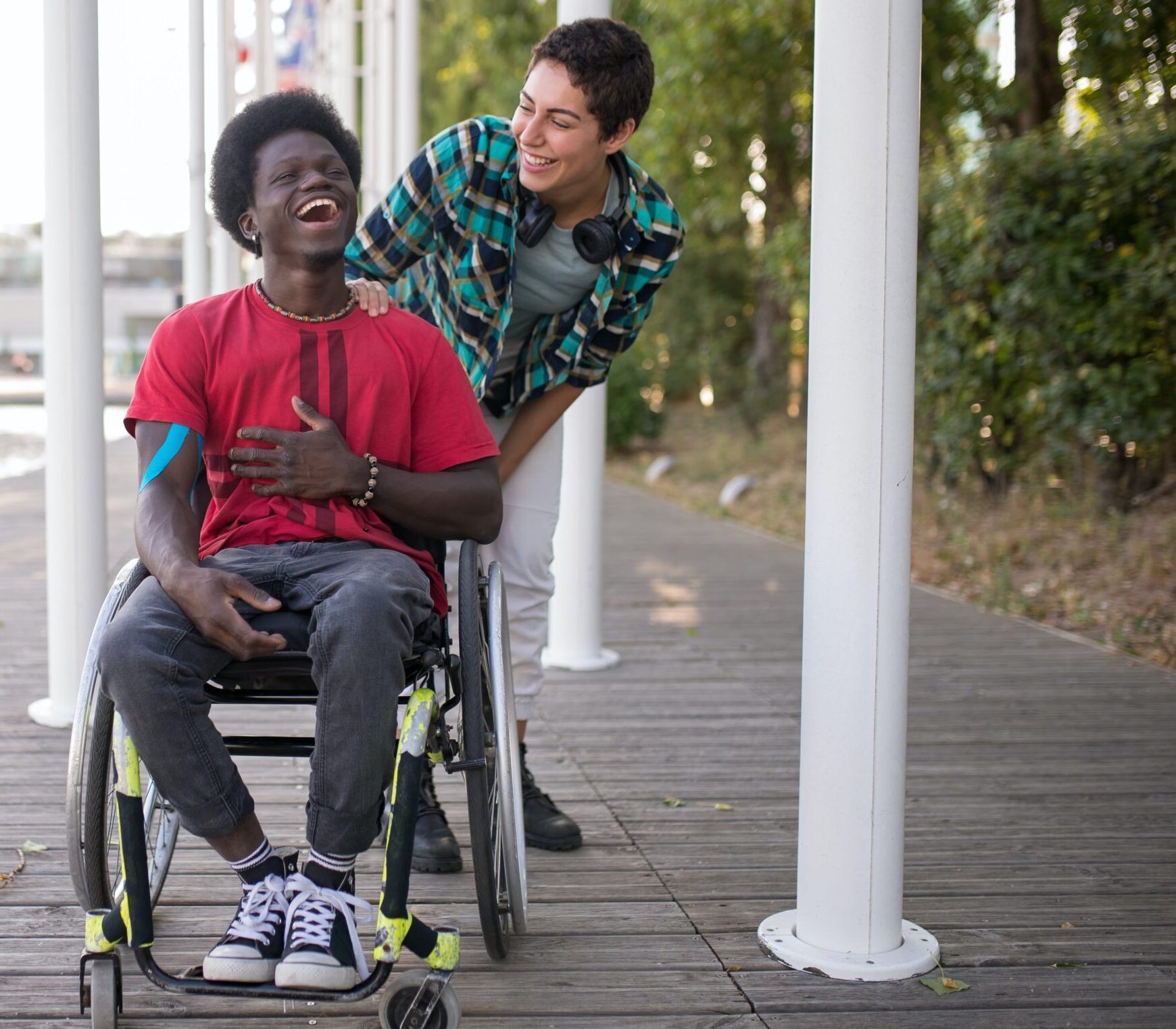 Black person sitting in a wheelchair with a companion standing behind